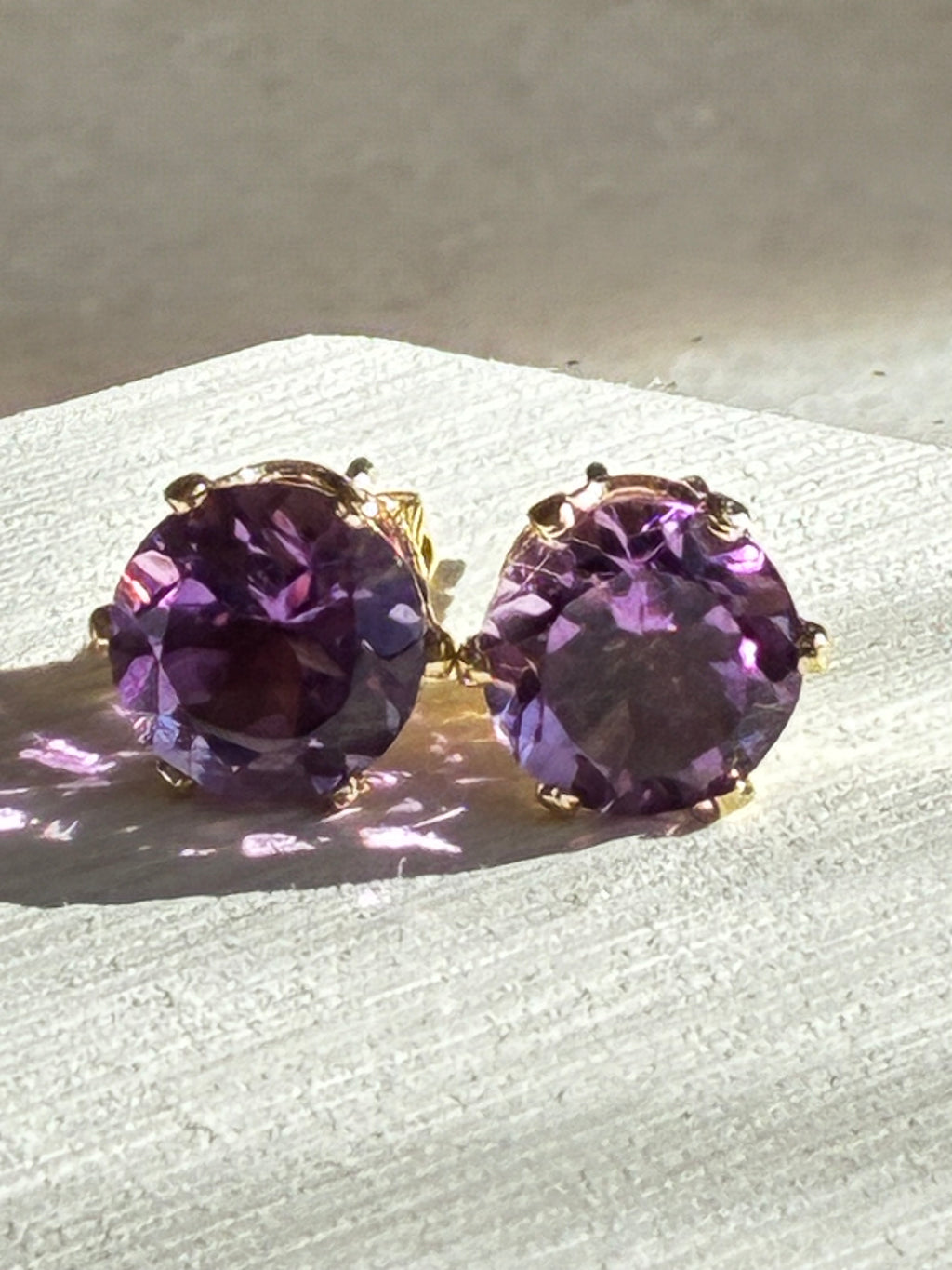 Pair of purple gemstone earrings on a white surface