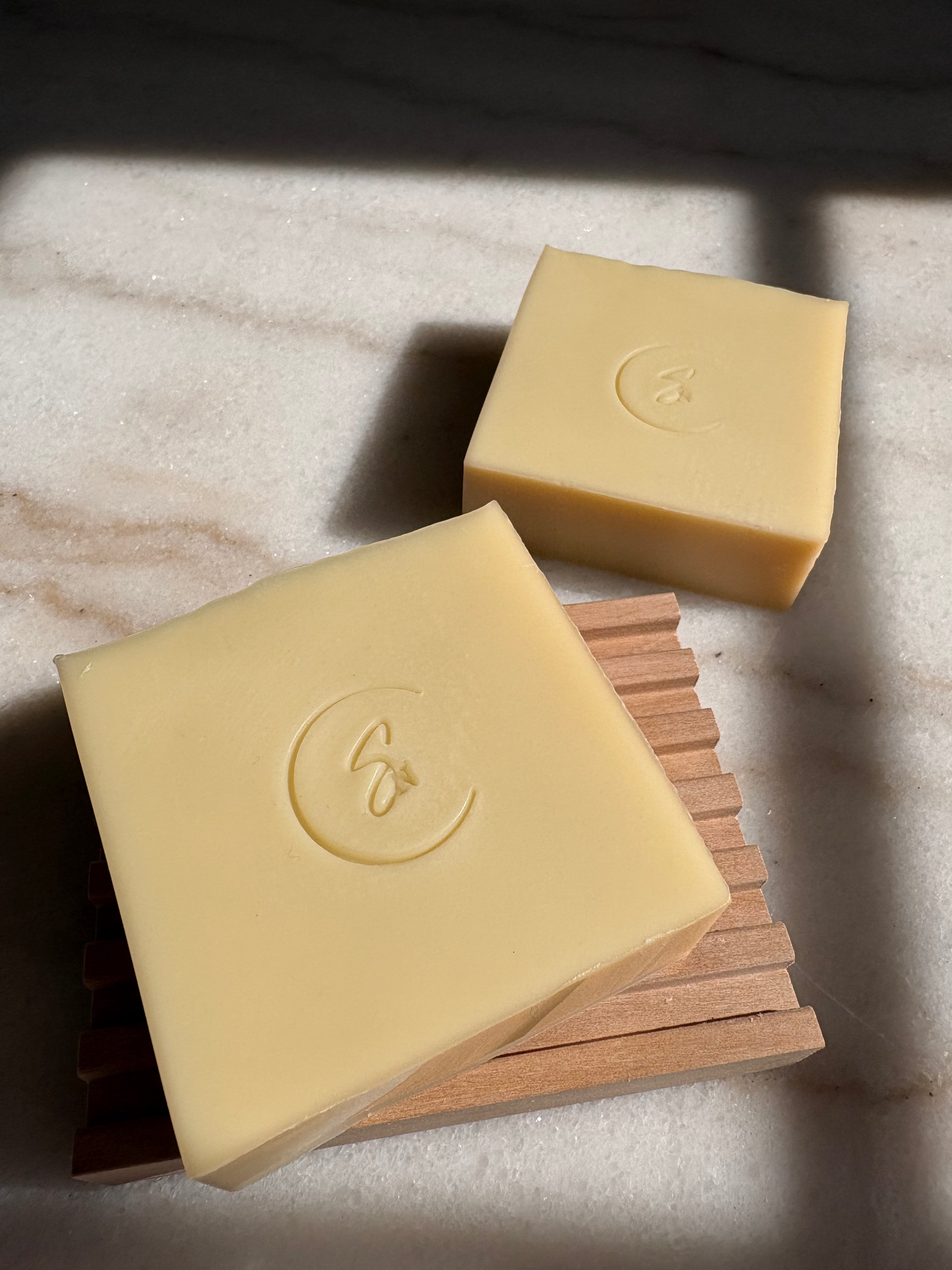 Chamomile soap on wooden soap dish. Close-up of chamomile handmade soap with creamy lather for sensitive skin.