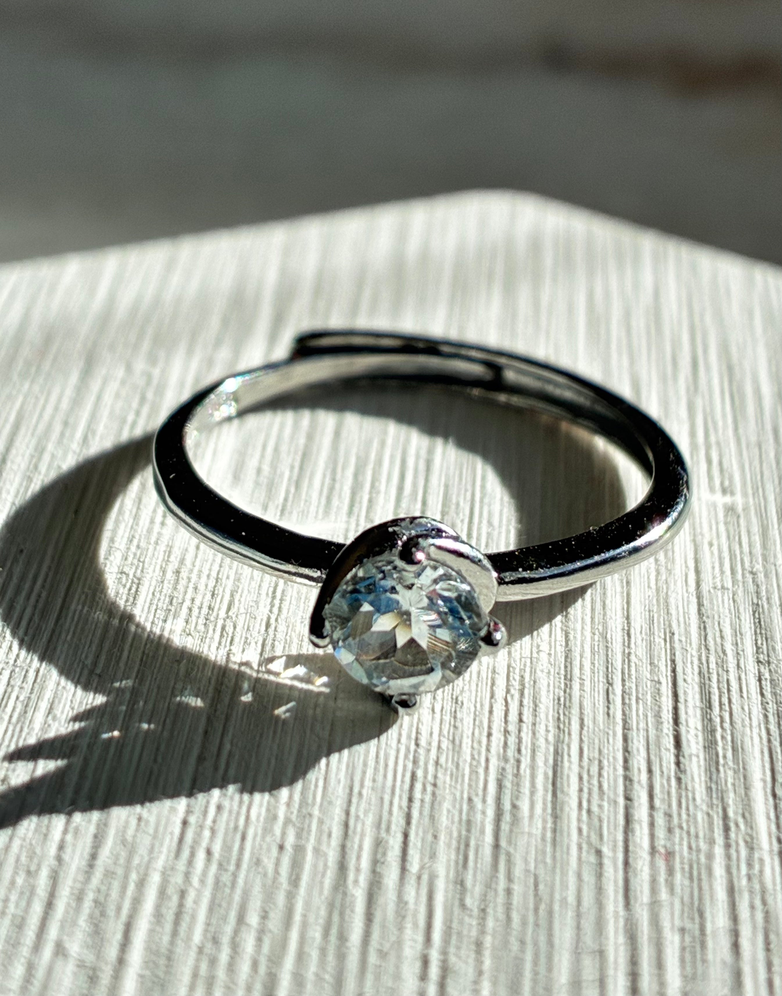 Silver ring with a clear gemstone on a textured surface