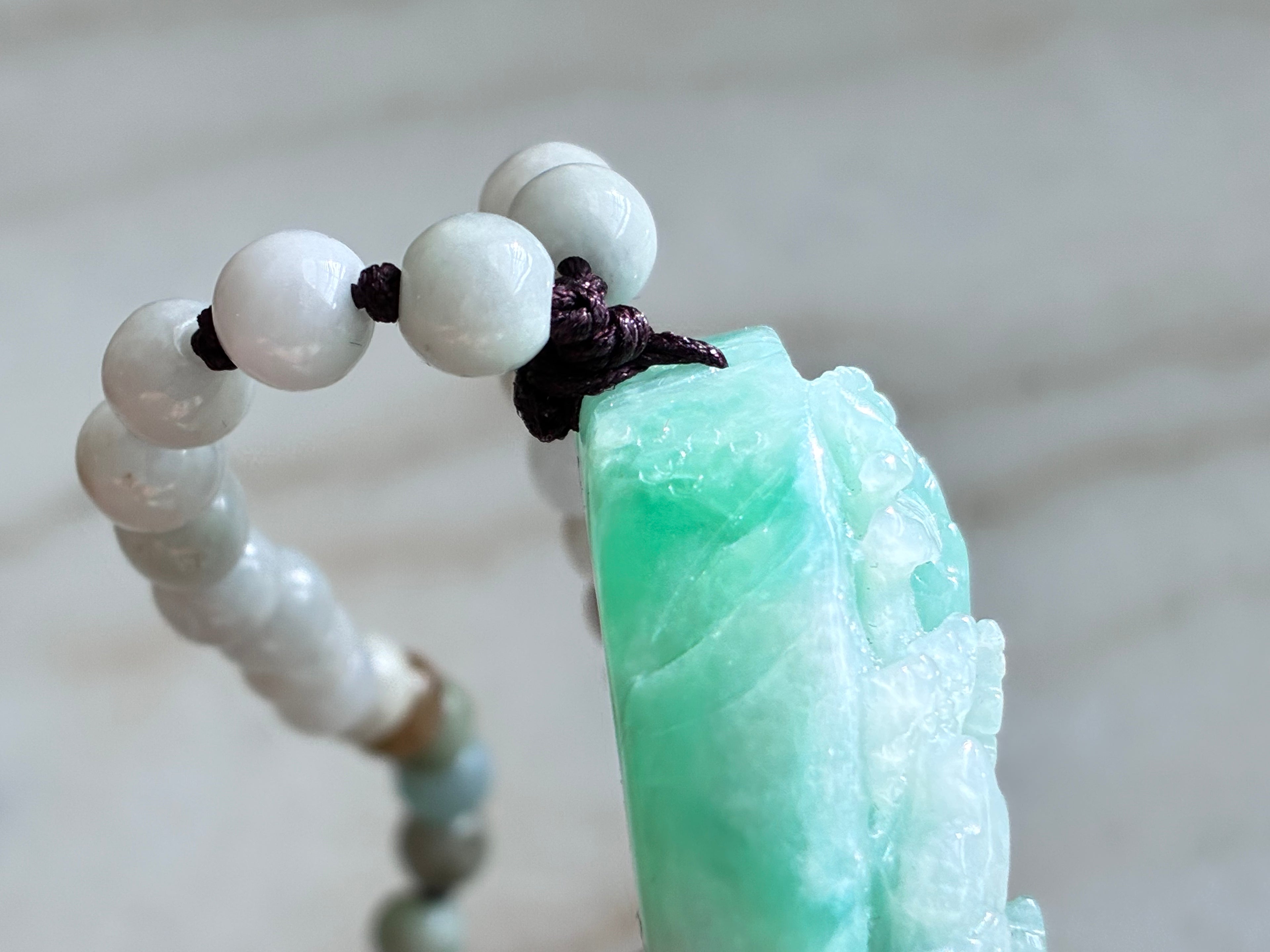 Close-up of a jade bracelet with a green crystal on a light background