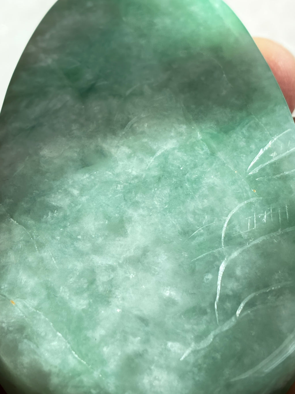 Close-up of a green jade stone with visible texture and markings.