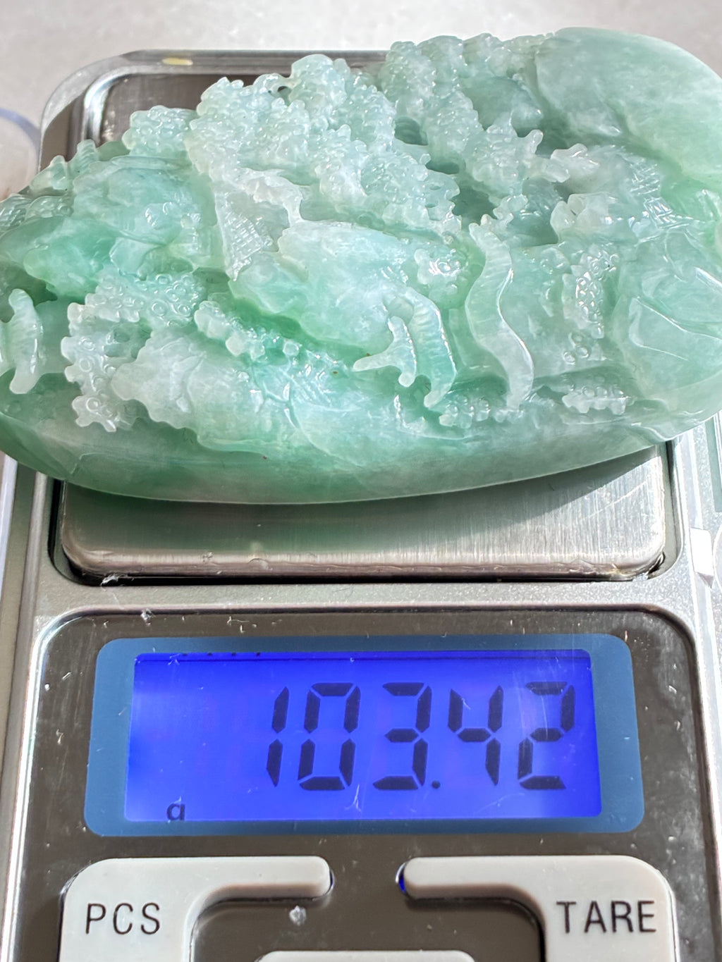 Jadeite Jade pendant on a digital scale displaying a weight of 103.42 grams.