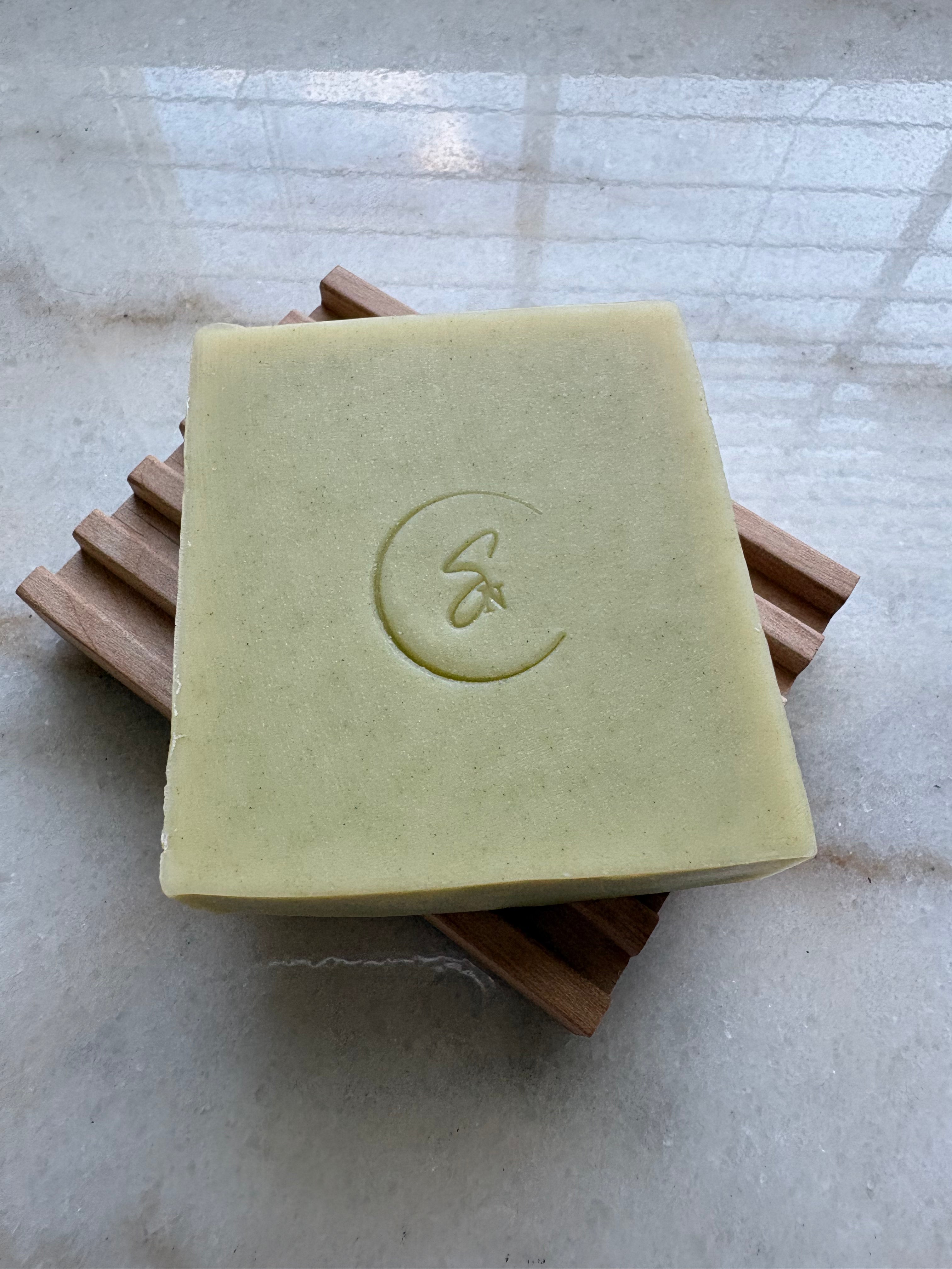 Handmade cucumber and aloe vera soap displayed on a natural wooden soap dish.