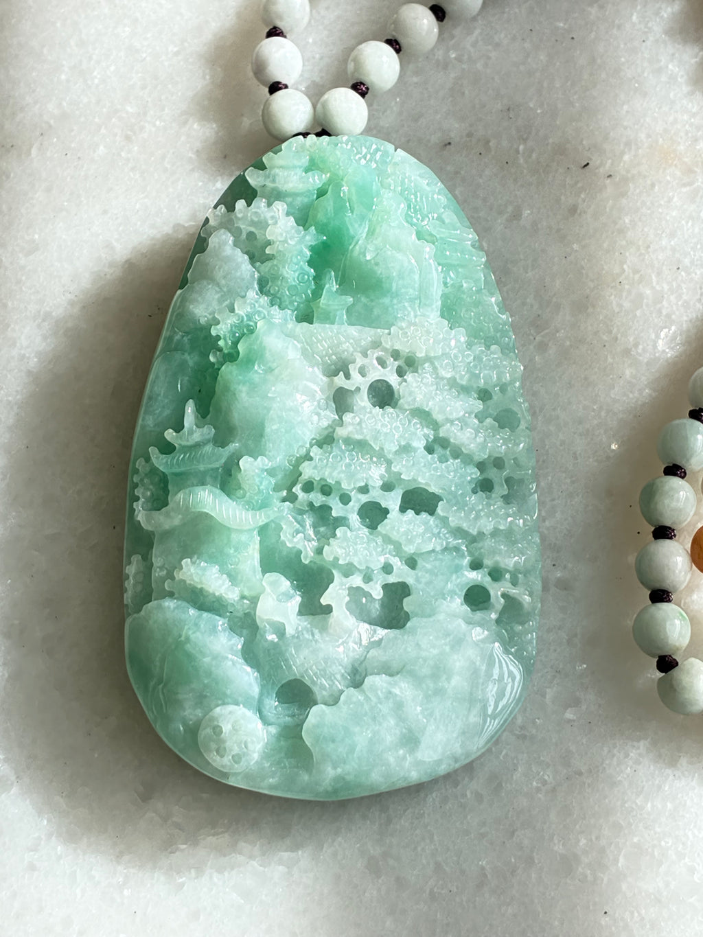 Jadeite Jade pendant with bead necklace on a light background