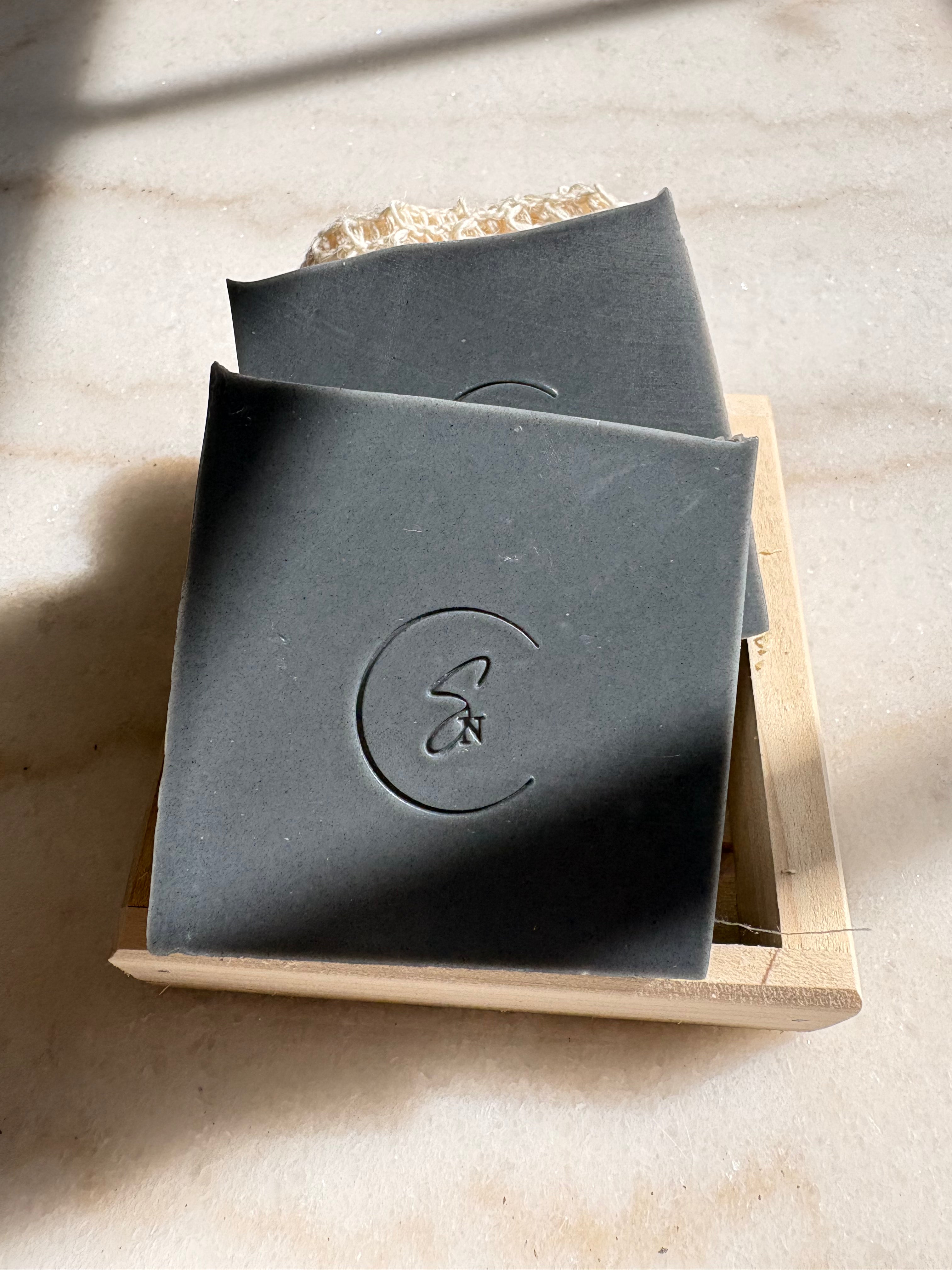 A sleek, obsidian-black Midnight Embers soap bar made with activated coconut charcoal, featuring a hand-cut artisanal edge."\