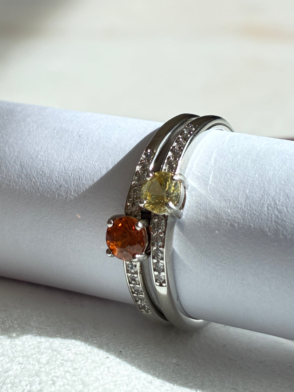 Two silver rings with gemstones on a white surface
