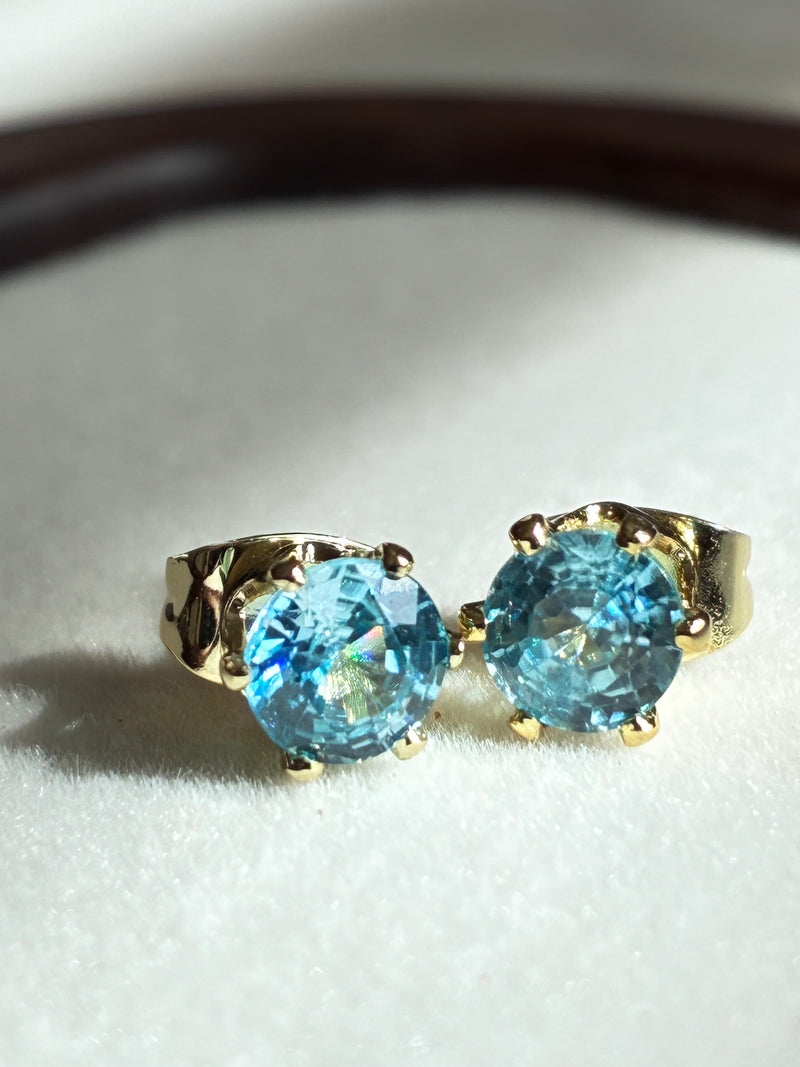 Gold earrings with blue gemstones on a white surface